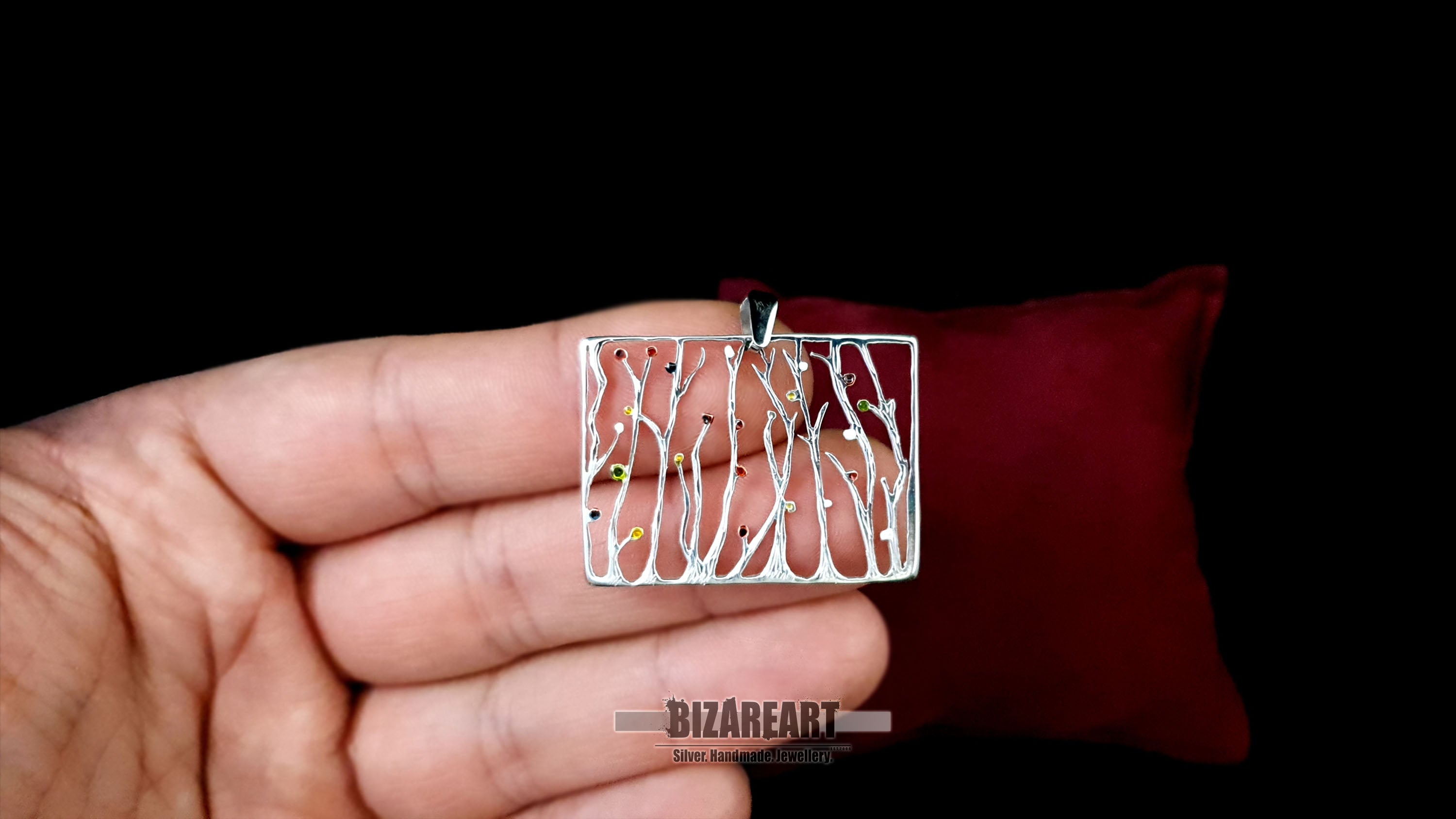 Close-up of the rectangular sterling silver seaweed pendant resting on a hand, demonstrating its real-life size, lightweight feel, and detailed craftsmanship.