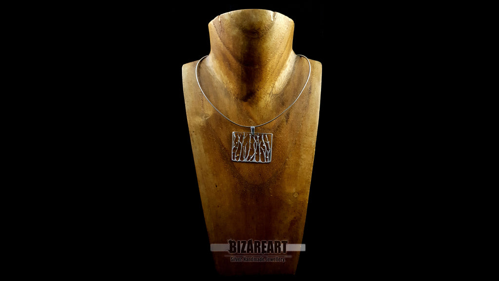 Front view of the silver seaweed openwork pendant necklace displayed on a rustic wooden neck mannequin to showcase its scale and hanging length.