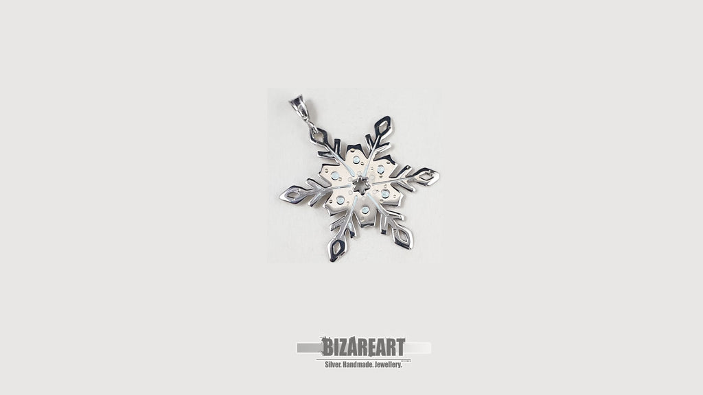 A front-facing studio shot of the sterling silver snowflake pendant centered on a clean, light gray background showing the intricate hand-sawn details.