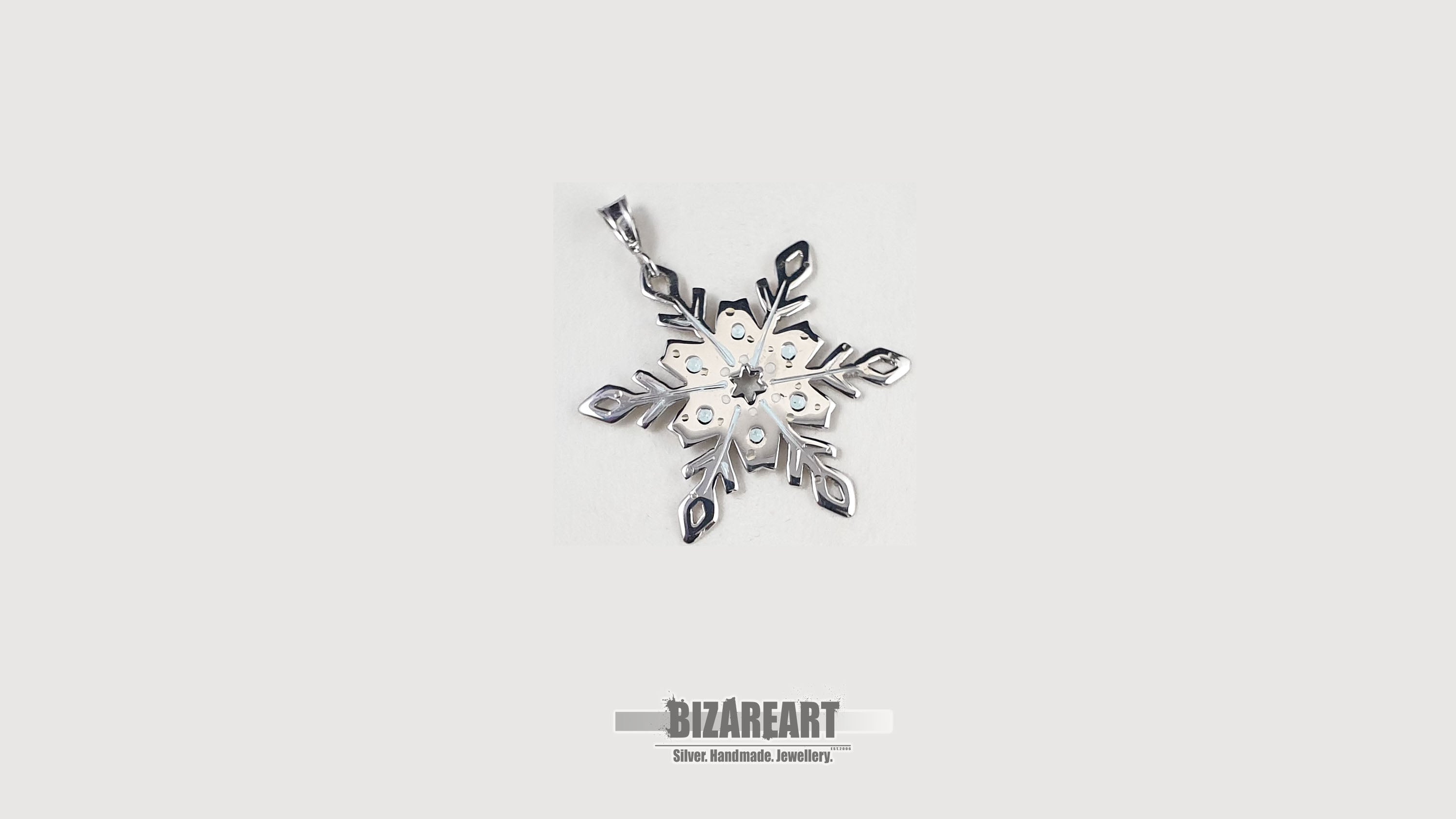A front-facing studio shot of the sterling silver snowflake pendant centered on a clean, light gray background showing the intricate hand-sawn details.